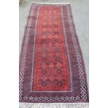 Belouch rug with an all-over stylised flowerhead design on a red ground with borders, 7ft 6ins x 3ft