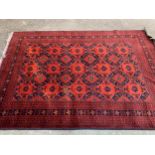Small Afghan carpet with an all-over stylised flowerhead and panel design in shades of deep red