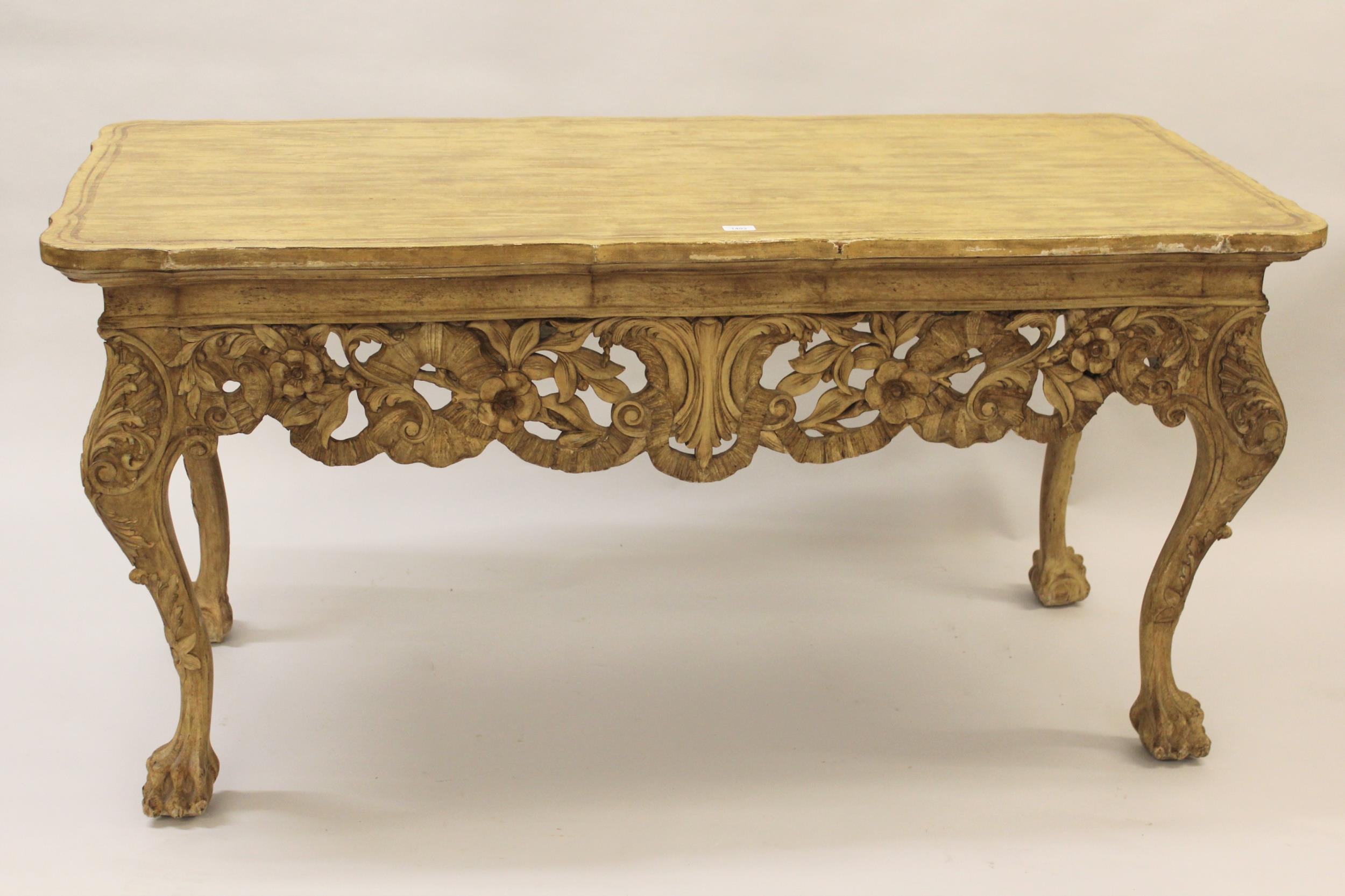 Carved and painted centre table in 18th Century Irish style, the shaped grained top above a carved