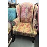 Late 20th Century wing back armchair, having floral and striped upholstery on stained beech cabriole
