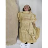 Small 1930's painted composition doll wearing a cream dress