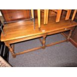 Ercol rectangular light elm coffee table on turned supports with stretchers, 44ins x 19ins x 16ins