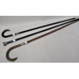 Two ebonised walking canes with silver mounts, and another natural form walking cane with silver