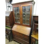 George III oak bureau bookcase, the moulded cornice above two lead glazed doors with pull-out candle