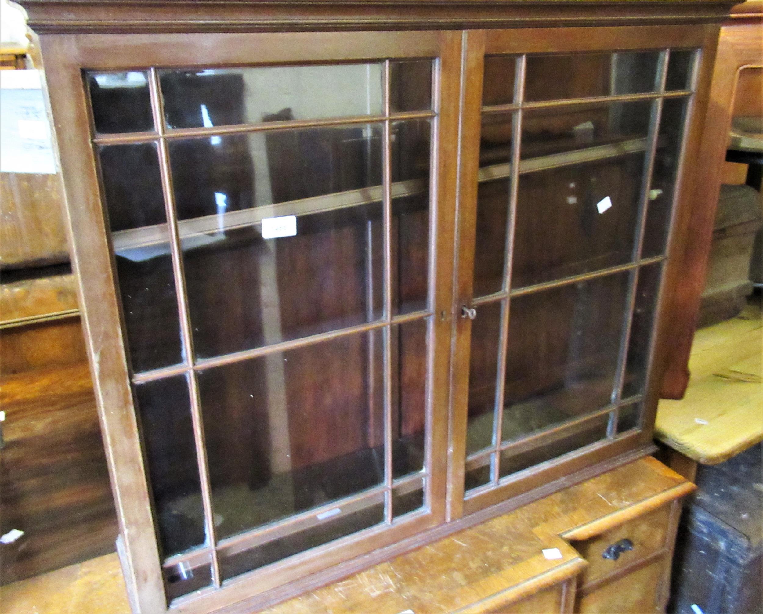 Mahogany wall cabinet with two glazed doors enclosing shelves above a shaped apron, 30.75ins wide