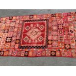 North African carpet with a medallion and all-over polychrome panel design in shades of pink, red,