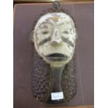 Native carved softwood and painted wall mask applied with seed pods, 15ins high