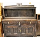 Oak dresser with an open shelf back above three carved drawers and two carved panelled doors, raised
