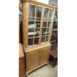 Small stripped pine bookcase, the moulded cornice above a pair of bar glazed doors, the base with