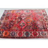 Kurdish rug with an all-over panel design in shades of deep red, orange and black with a rosette