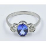 Platinum ring set with an oval central tanzanite flanked by two diamonds This is a modern ring in '