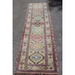 Kurdish runner with repeating polychrome medallion design, 8ft 10ins x 2ft 8ins approximately (