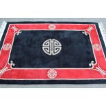 Modern Chinese rug with a circular centre medallion on a black ground with red border, 6ft x 4ft