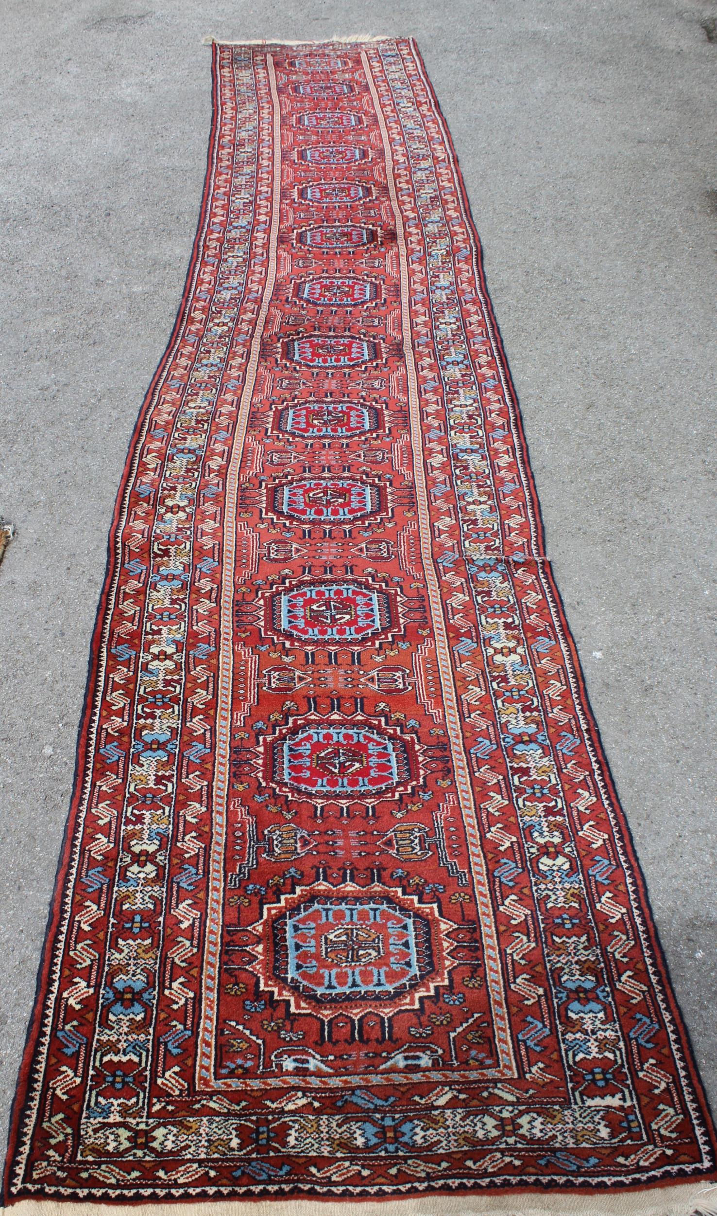 Indo Persian runner of Afghan design with a repeating hooked medallion pattern, on a rose ground