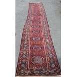Indo Persian runner of Afghan design with a repeating hooked medallion pattern, on a rose ground