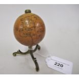 19th Century nut formed as a miniature globe, with scrimshaw decorated surface, on a brass stand,