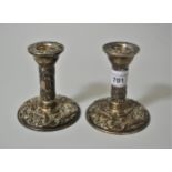 Pair of small silver circular embossed candlesticks In good condition but could benefit from a