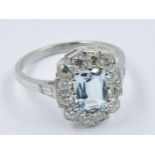 Platinum dress ring set with a single central aquamarine within a diamond surround This is a