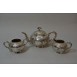 Chinese silver three piece tea service of circular squat baluster form decorated with relief