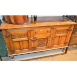 Reproduction oak dresser base with centre drawer and carved panel door flanked by two further doors,