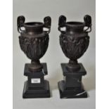Pair of 20th Century cast bronze two handled urns on marble bases, 13.5ins high In good condition,