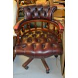 Reproduction mahogany red leather button upholstered office armchair on swept supports and casters