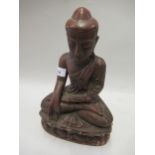Burmese red patinated carved wooden seated Buddhistic figure, 12ins high