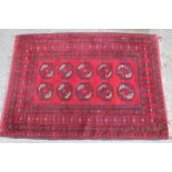 Small Afghan rug with repeating gol design on a red ground 122cm x 89cm