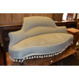 Late Victorian upholstered occasional sofa, the shaped back above an overstuffed seat, tasselled