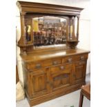 Art Nouveau oak sideboard, the mirrored back flanked by floral carved panels and turned pilasters