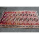 Central Persian rug of Turkoman design with two rows of gols on a rose ground with borders, 7ft 8ins