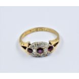 18ct Gold ruby and diamond dress ring, the oval head with three small rubies surrounded by ten small