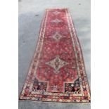 Hamadan runner with a medallion and all-over stylised floral design on a red ground with borders,