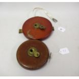 Two circular leather cased tape measures