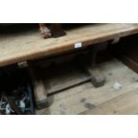 Primitive oak trestle table / bench, the plank top on rectangular cut chamfered supports with shaped