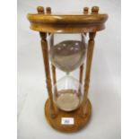 Large modern glass sand timer on a pine stand