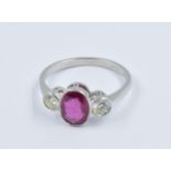 Platinum ring set central oval ruby flanked by two circular cut diamonds, size N Good overall