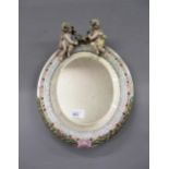 German porcelain oval mirror surmounted by two figures of cherubs 29cm tall x 26cm wide Various