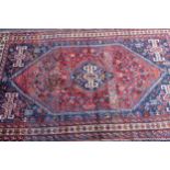 Large Shiraz rug with a medallion and all-over stylised design on a red ground with blue corner