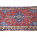 Small Kurdish rug with a lobed medallion and all-over stylised floral design on a brick red field