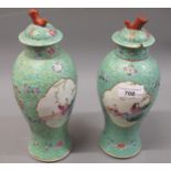 Pair of 20th Century Chinese baluster form vases with covers, decorated in famille rose colours on a