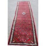 Hamadan runner with a medallion and all-over Herati design on a red ground with borders, 9ft 8ins