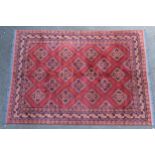 Afghan carpet with an all-over hooked floral medallion design on a madder ground with multiple