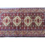 Small Indo Persian rug with an all-over stylised design on a red ground with borders