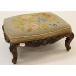 Victorian rosewood footstool with a floral needlework seat above a carved frieze and low cabriole