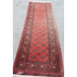Afghan runner with repeating gol design on a red ground with borders, 9ft 8ins x 2ft 10ins