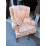 Floral upholstered wing back armchair, raised on carved cabriole claw and ball front supports