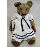 Early 20th Century straw filled articulated teddy bear in blue and white dress, (teddy at fault),