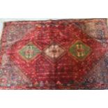 Qashqai rug with a triple medallion design on a wine red ground with corner designs and narrow