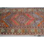 Kurdish rug with central hooked medallion and multiple borders on a red and brown ground, 190 x
